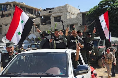 Syrian police units wave the national flag as they enter the town of Douma, Eastern Ghouta, on April 14, 2018 as the last of the rebel fighters who held the town for more than four years departed under an evacuation deal with the government. Sana via AP