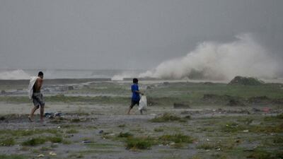 Residents sift through the shoreline amidst a storm surge brought about by powerful typhoon Haiyan at Legazpi. Nelson Salting / AP Photo