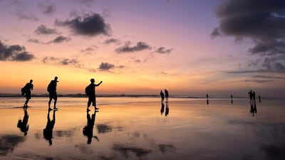 Tourists take selfies at sunset on Seminyak Beach in Bali. AP