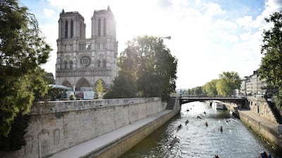 Rowers scull past Notre Dame Cathedral as they take part in La Traversee de Paris en Aviron on the Seine. AFP