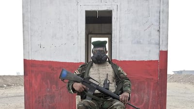 Raad Muqdam Al-Mosieh, 35, from Baghdad, Iraq, an Iraqi army soldier, poses for a portrait as he guards a checkpoint while wearing a gas mask on the outskirts of Qayara.
