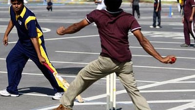 Two teams play in a company cricket match held in an Abu Dhabi car park.