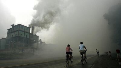Cyclists pass through thick pollution from a factory in Yutian in China's northwest Hebei province. (AFP PHOTO / FILES / Peter PARKS)