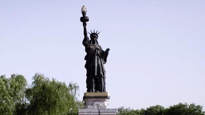 A young man hardstanding by a mini replica of the Statue of Liberty.