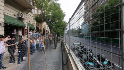 Spectators watch the race from behind a fence as Mercedes' Lewis Hamilton drives past. Reuters