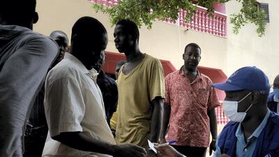 An International Organisation for Migration agent, right, distributes economic subsidies for migrants repatriated from Niger to Bamako in July, 2020. AFP