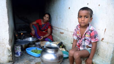 Tribal child K. Jagan (R), who lost his father in a road accident, sits with his mother K. Mangi at their home. Noah Seelam / AFP