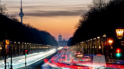 Cars move towards the Brandenburg Gate as the sun sets in Berlin. AP