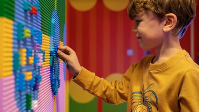 A boy plays with the Lego wall inside the installation