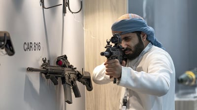 A exhibition visitor looks through the scope of a Caracal CAR 816 Assault Rifles. Victor Besa/The National