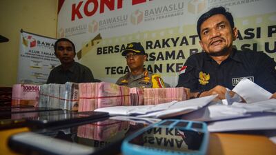 Indra Khalid Nasution (R), head of the Elections Supervisory Agency (Bawaslu) and police display seized money, believed to be distributed to influence voters ahead of the upcoming general elections.