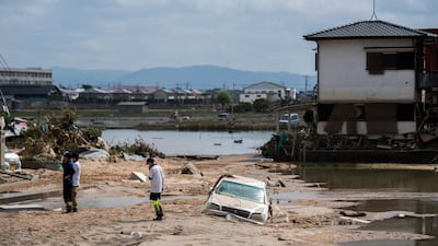 People inspect their damaged homes in a flood hit area in Mabi, Okayama. AFP