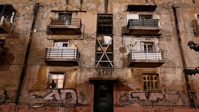 A man is silhouetted speaking on the phone inside an apartment.