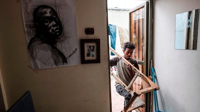 Eritrean artist Nebay Abraha, 23, enters his room and studio carrying an easel. AFP
