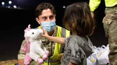 A member of the RAF hands a child a toy as passengers evacuated from Afghanistan leave a British military aircraft at Brize Norton airbase in southern England on Thursday. AFP