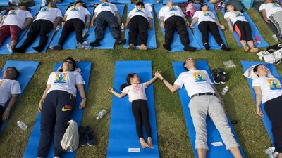 A man and child hold hands as they participate in a mass yoga session at the grounds of Chulalongkorn University in Bangkok. Romeo Gacad / AFP