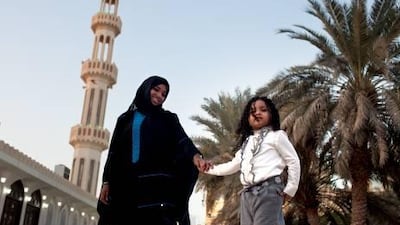 Full-time worker and a mother of two, Noura al Falahi poses for a portrait with her 3-year-old daughter Ghala al Remethi on Sunday, Jan. 1, 2012, in the her neighborhood in Abu Dhabi.