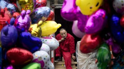 A worker takes a break on a lorry loaded with goods in between balloons sold by vendors in Beijing, China. Andy Wong / AP Photo