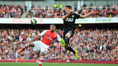 Arsenal's Alex Oxlade-Chamberlain, left, and Hull City's Gaston Ramirez, right, both lunge at the ball during the clubs' 2-2 draw on Saturday at the Emirates Stadium in London. Glyn Kirk / AFP