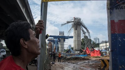 A man stands near a collapsed girder pole on a construction site in Jakarta, Indonesia. Antara Foto / Aprillio Akbar / via Reuters