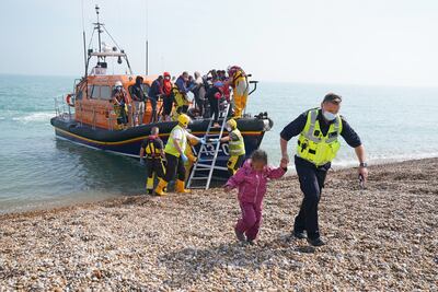 A little girl is helped ashore by a Border Force agent in Kent after arriving on a small boat from France. Getty