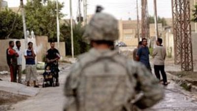Iraqis observe a US soldier as he patrols the Baghdad suburb of Sadiyah last June.