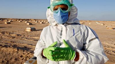 Abdelhussan Kadhim, from the PMF, who volunteered to work in the cemetery, wearing a protective suit and poses for the camera at the new Wadi Al Salam cemetery for those who died of the coronavirus. Reuters
