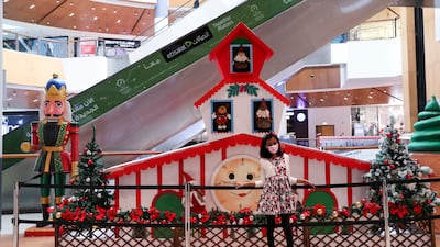 A young girl poses in front of the Christmas gingerbread house decoration at Al Wahda Mall, Abu Dhabi. Khushnum Bhandari / The National