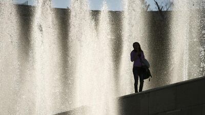 A woman walks by water fountains as she enjoys the warm weather in Paris. Alain Jocard / AFP Photo