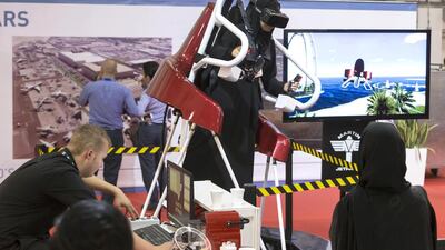 A show goer tries out the Martin Jetpack flight simulator while others watch at the 2015 Dubai Air show held at Dubai World Central. Antonie Robertson / The National