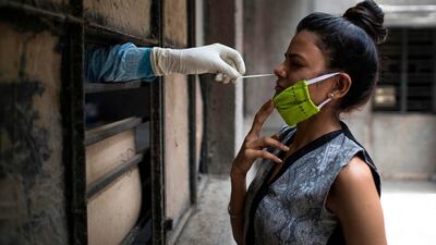 A health official collects a swab sample from a woman in New Delhi, India. AFP