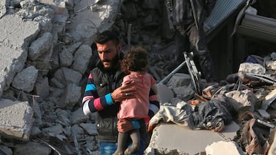 A Syrian man carries a child following an airstrike on the rebel-held town of Atareb in Syria's northern Aleppo province. AFP PHOTO / Zein Al RIFAI