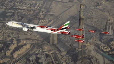 A formation of nine Royal Air Force Red Arrows Hawk aircraft fly alongside a Boeing 777 aircraft on the occasion at the Dubai Airshow. Red Arrows / AP Photo