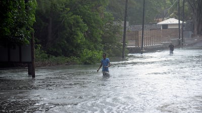 A man walks through a flooded road in Mauritius. AP Photo