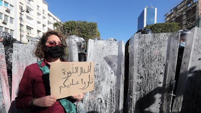 A protester holds a placard reading in Arabic 'Children of the revolution revolted against you' in front of anti-riot policemen during a demonstration in Tunis. EPA