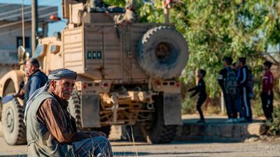 A Syrian elderly man sits near a US armoured vehicle on patrol in the village of Ein Diwar in Syria's northeastern Hasakeh province. AFP