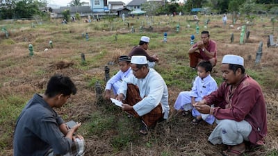 Thai Muslims pray before the tomb of their relatives at a cemetery during the Eid Al Adha festival in Thailand's southern province of Narathiwat. AFP