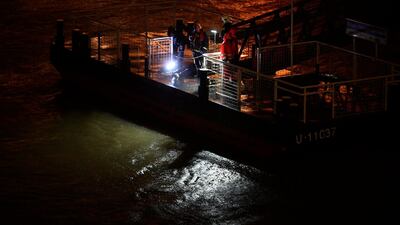 Rescuers and police officers inspect the dark water from a landing dock after a tourist boat crashed with another ship, overturned and sank in River Danube, in Budapest, Hungary, killing at least three of the 34 people. EPA