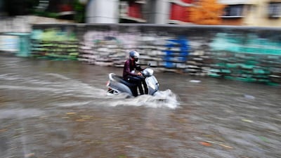 A man rides a scooter through a waterlogged street in Mumbai after heavy rainfall from Cyclone Tauktae. AFP