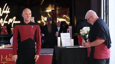 A visitor writes a message of remembrance next to a wax figure of Patrick Stewart at Madame Tussauds museum in Hollywood, California. AFP