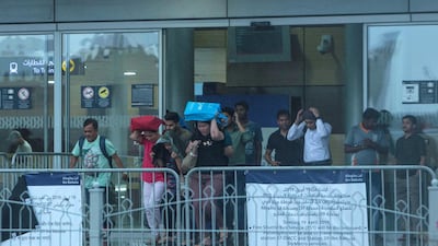 Commuters battle the elements at Ibn Battuta Metro Station. Leslie Pableo / The National