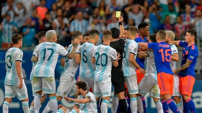 Peruvian referee Diego Haro awards a yellow card to Colombia's Juan Cuadrado after fouling Argentina's Lionel Messi. AFP