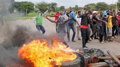 Protesters stand behind a burning barricade during protests on a road leading to Harare, Zimbabwe, January 15, 2019. Reuters