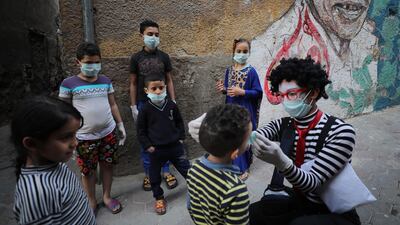 Egyptian clown Ahmed Naser wears a face mask and helps children to put on face masks as a preventive measure against the spread of the coronavirus disease, in Darb Al-Ban district, Cairo, Egypt. EPA