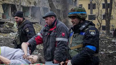 Ukrainian emergency employees and volunteers carry the injured pregnant woman from a maternity hospital in Mariupol. AP Photo