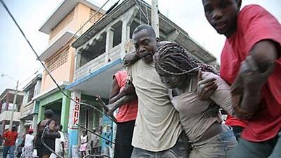 A woman is helped to walk after being trapped in rubble in Port-au-Prince following a huge earthquake measuring 7.0.
