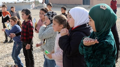 Refugee children dance outside a makeshift shelter in Lebanon, near the border with Syria. EPA