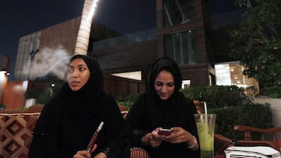In this file photo, a Saudi woman smokes tobacco from a waterpipe while sitting in a coffee shop with a friend in Jeddah, Saudi Arabia. The number of single Saudi women in the kingdom is on the rise, a trend scoffed at by conservatives. Hassan Ammar/AP Photo