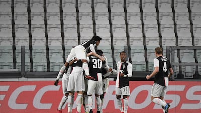 Juventus players celebrates after scoring their opener against Inter Milan in an empty stadium. AFP
