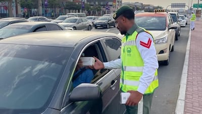 A Dubai Police officer distributes an iftar meal to a motorist in the emirate. Photo: Dubai Police